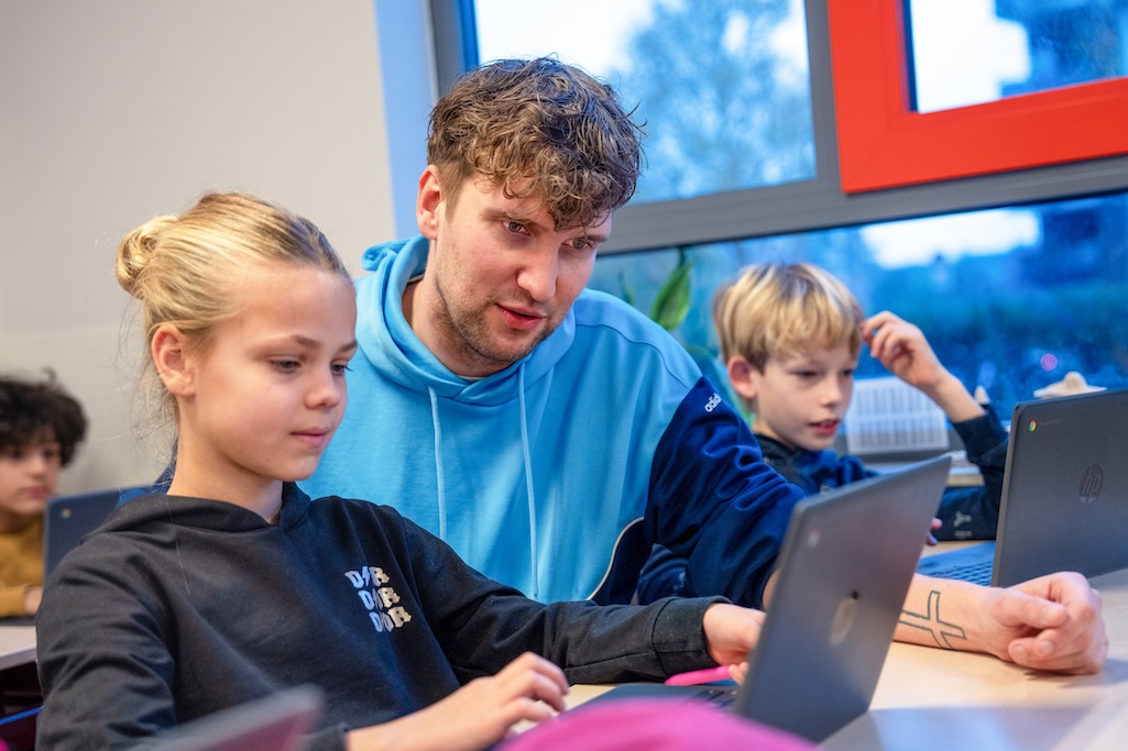 Leerling werkt op computer en de leraar helpt
