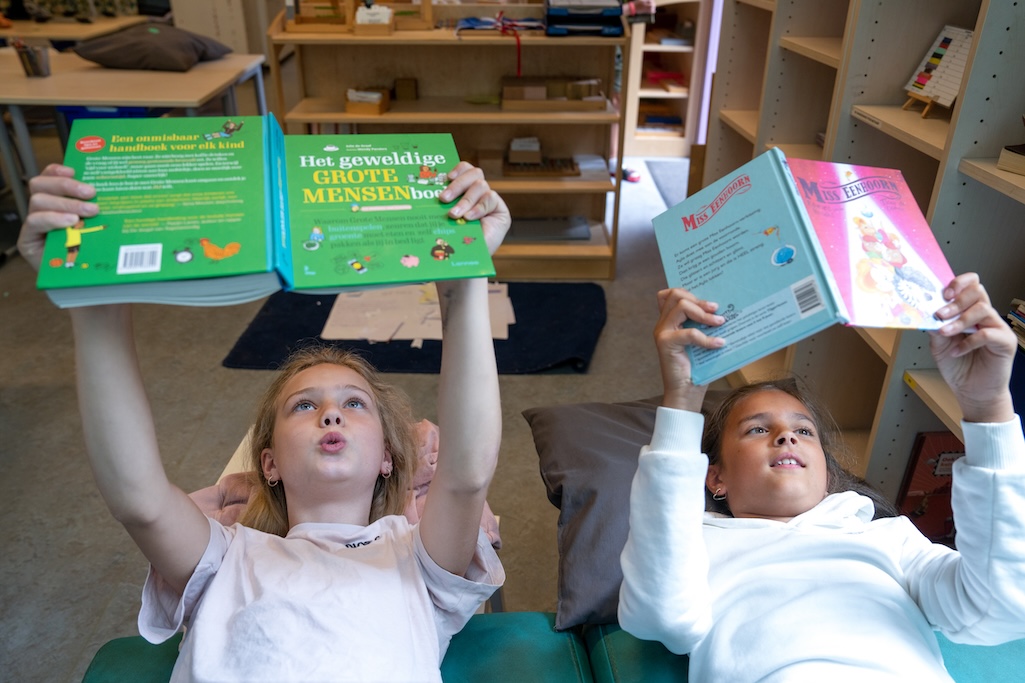 Kinderen lezen boek op hun rug in een klaslokaal